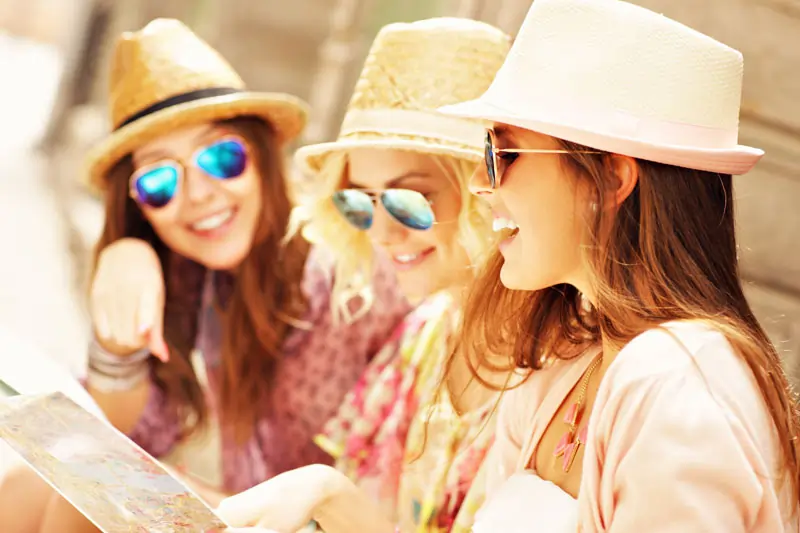 Drei Frauen lesen zusammen eine Karte und lachen, was das Loslassen, emotionale Selbstpflege und das Entdecken neuer Interessen durch gemeinsame Aktivitäten zeigt.