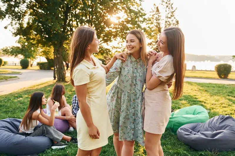 Drei glückliche Frauen umarmen sich im Park, symbolisieren den Neuanfang und das Glück nach einer Trennung.