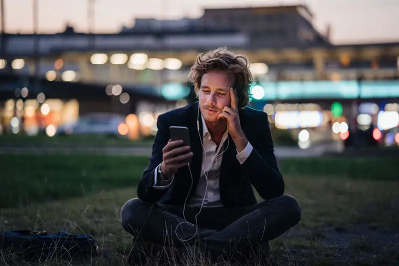 Ein nachdenklicher Mann, der auf sein Handy schaut, zeigt Anzeichen dafür, dass er vielleicht zurückkommt.