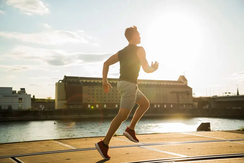 Junger Mann joggt am Fluss bei Sonnenaufgang, steht für einen Neuanfang und die Chance, das eigene Leben nach einer Trennung neu zu gestalten.